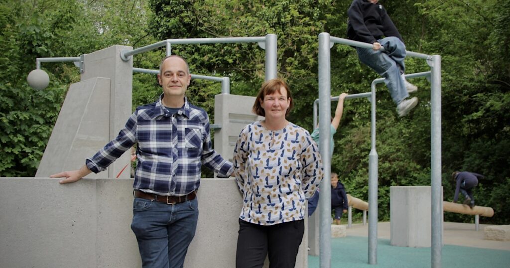 Der SPD-Bezirksverordnete Rainer Ziffels und SPD-Stadträtin Carolina Böhm stehen vor einem Klettergerüst mit Kindern